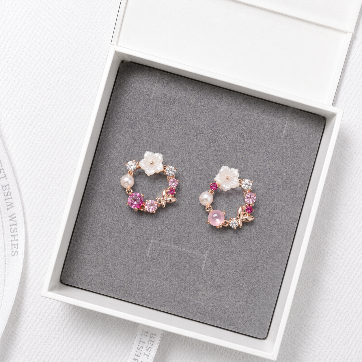 Pink floral crystal stud earrings with pearl accents and rose gold details displayed in a luxury gift box.