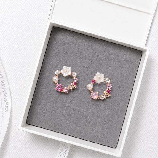Pink floral crystal stud earrings with pearl accents and rose gold details displayed in a luxury gift box.